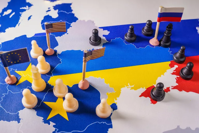 Flaggen der EU, der USA und Russlands mit Schachfiguren, die den Konflikt und die Kontrolle über die Ukraine symbolisieren (Symbolbild)
